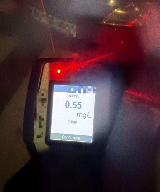 Breathalyzer device displaying a reading of 0.55 mg/L on the screen with a red indicator light nearby, blurred background.