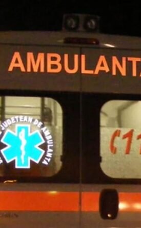 Rear view of a white ambulance at night with orange stripes; 'AMBULANTA' on the back, a blue Star of Life logo, and '112' on the window.