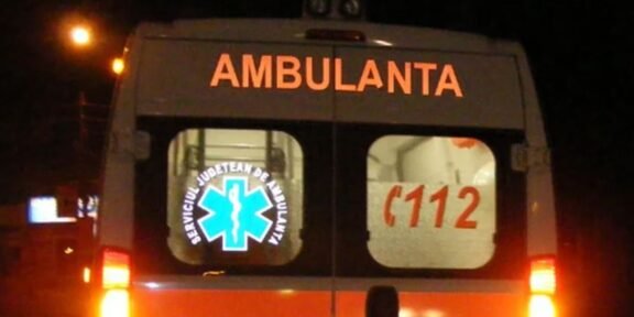 Rear view of a white ambulance at night with orange stripes; 'AMBULANTA' on the back, a blue Star of Life logo, and '112' on the window.