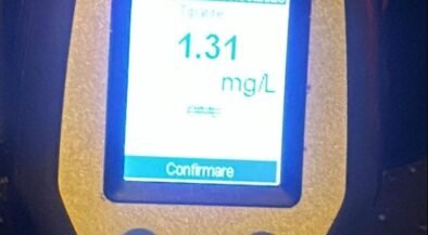 Portable meter showing a reading of 1.31 mg/L with Italian interface and 'Confermare' button, yellow device body.