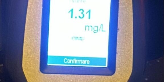 Portable meter showing a reading of 1.31 mg/L with Italian interface and 'Confermare' button, yellow device body.