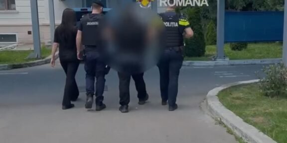 Police officers escorting a blurred person down a street near a building entrance with a blue canopy; 'Politia Romana' emblem visible