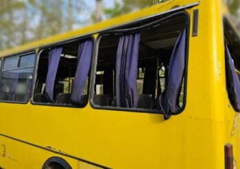 Yellow school bus with open windows and purple curtains, parked outdoors