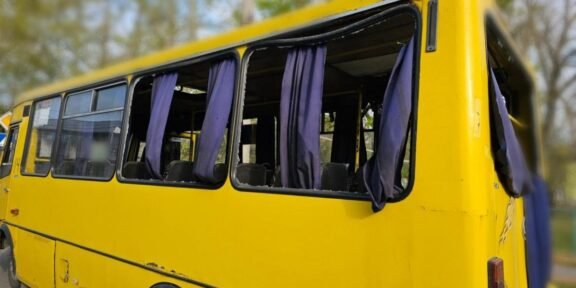 Yellow school bus with open windows and purple curtains, parked outdoors