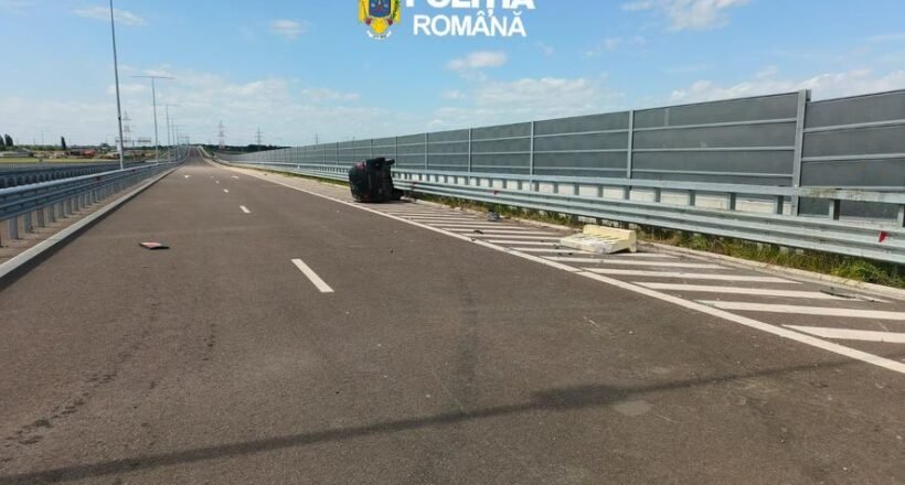 Wide highway scene with an overturned dark car on the right shoulder near the barrier; police logo reads 'Poliția Română'.
