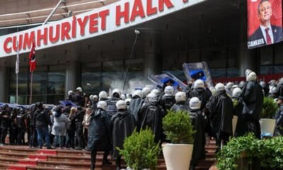 Riot police in helmets and shields facing a crowd outside a building with a large red sign that reads Cumhuriyet Halk.