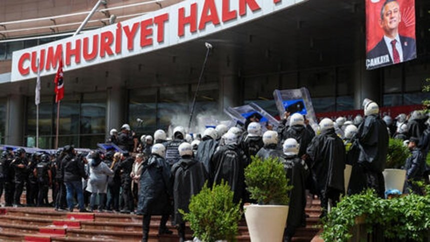 Riot police in helmets and shields facing a crowd outside a building with a large red sign that reads Cumhuriyet Halk.