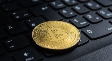Gold Bitcoin coin resting on a black computer keyboard in close-up.