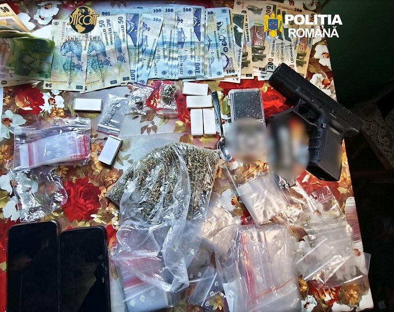 Romanian police display confiscated items on a table: euro banknotes, small bags of drugs, a handgun, and several smartphones.