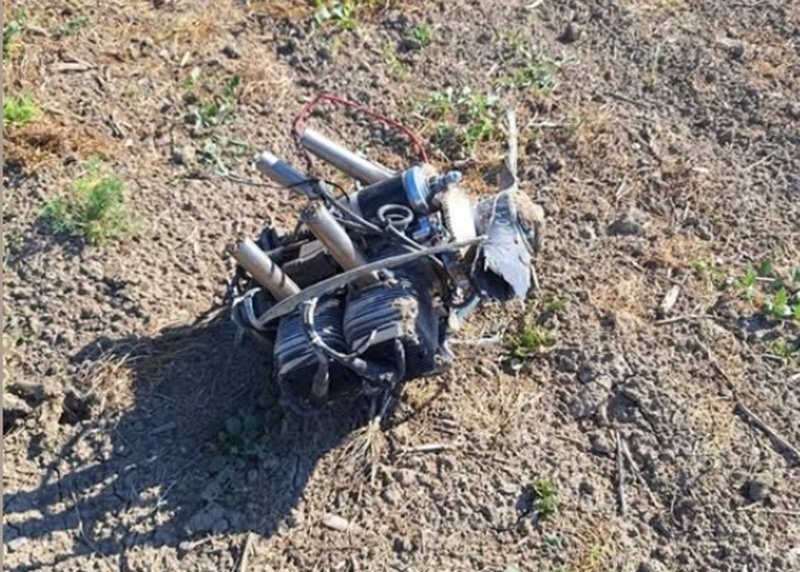 Mess of tangled wires and metal tubes on dry, rocky ground outdoors.