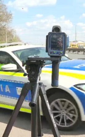 Romanian police car on a road with a speed camera mounted on a tripod in the foreground.