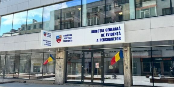 Front of a government building with Romanian flags and a blue sign reading 'Direcția Generală de Evidență a Persoanelor' above the doors (Constanța county office).