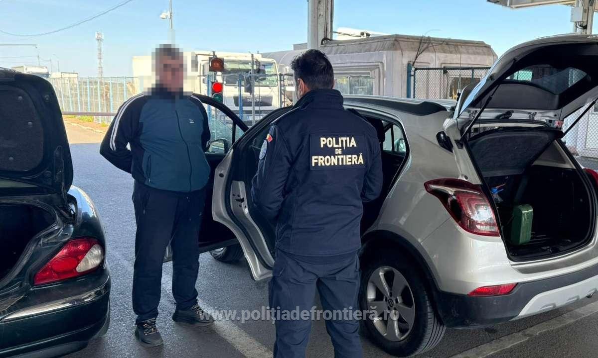 Border police officer in a dark uniform talks to a man at a car with the trunk open at a checkpoint. Frontière police patch visible on the jacket (text: POLIŢIA DE FRONTIERĂ).