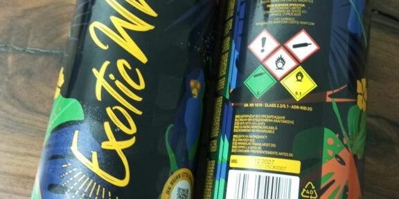 Two black plastic bottles with vibrant tropical graphics and yellow script reading exot(ic) on a wooden surface (front view).