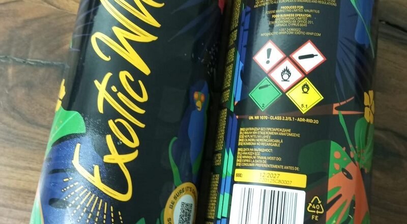 Two black plastic bottles with vibrant tropical graphics and yellow script reading exot(ic) on a wooden surface (front view).