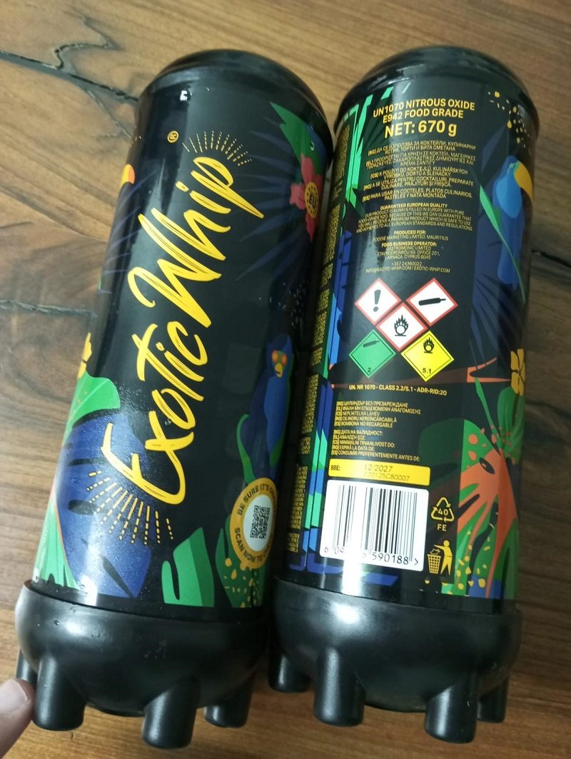 Two black plastic bottles with vibrant tropical graphics and yellow script reading exot(ic) on a wooden surface (front view).