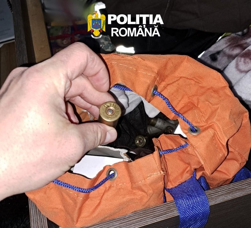 Close-up of a hand holding a brass shotgun shell over an orange bag with blue cords; inside are more shells, Romanian police logo visible