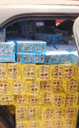 Car trunk loaded with yellow and blue boxed goods stacked to the roof of the cargo area