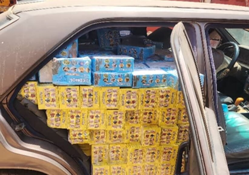 Car trunk loaded with yellow and blue boxed goods stacked to the roof of the cargo area