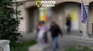 Blurry outdoor scene outside a building with the Romanian Police logo at the top, a European flag on a pole, and several people walking by.