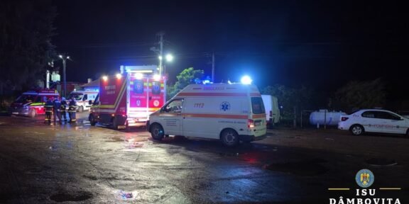 Nighttime emergency scene with ambulances and fire trucks, responders on a wet street with flashing lights.