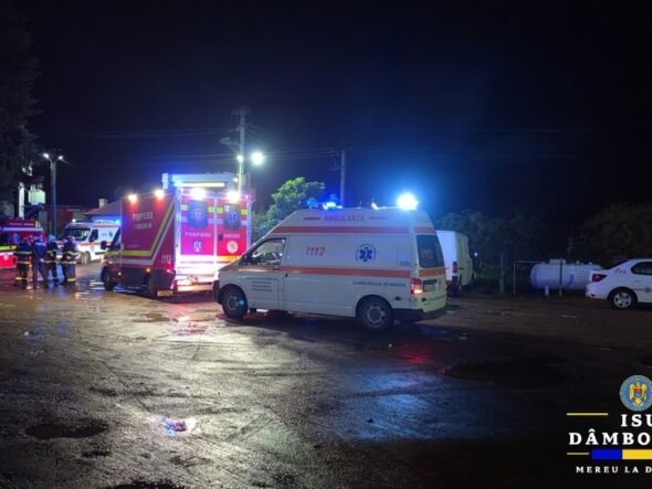 Nighttime emergency scene with ambulances and fire trucks, responders on a wet street with flashing lights.