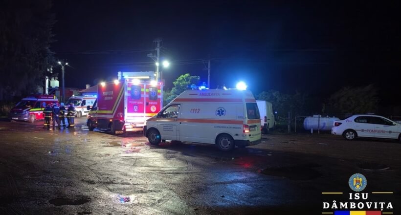 Nighttime emergency scene with ambulances and fire trucks, responders on a wet street with flashing lights.