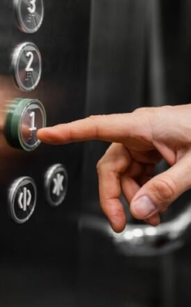 Person pressing the '1' floor button on an elevator panel.