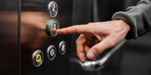 Person pressing the '1' floor button on an elevator panel.