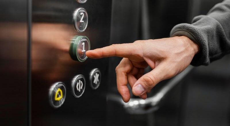 Person pressing the '1' floor button on an elevator panel.