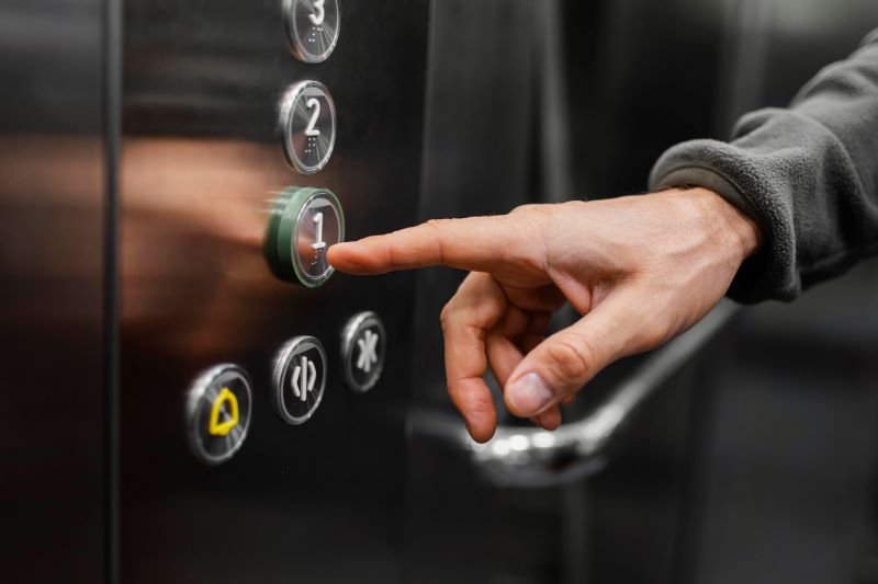 Person pressing the '1' floor button on an elevator panel.