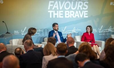 Panel discussion with three speakers on stage; backdrop reads 'Fortune Favours The Brave'.