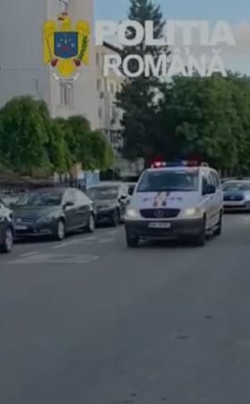Line of Romanian police cars on a city street with a white van in front and flashing blue lights; 'Politia Romana' watermark and crest visible above.