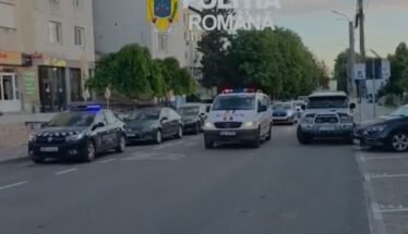 Line of Romanian police cars on a city street with a white van in front and flashing blue lights; 'Politia Romana' watermark and crest visible above.