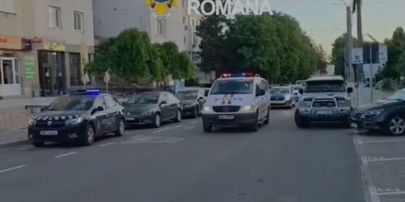 Line of Romanian police cars on a city street with a white van in front and flashing blue lights; 'Politia Romana' watermark and crest visible above.