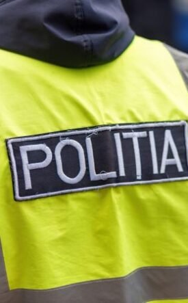 Rear view of a police officer wearing a neon yellow reflective vest with a POLITIA patch on the back.