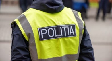 Rear view of a police officer wearing a neon yellow reflective vest with a POLITIA patch on the back.