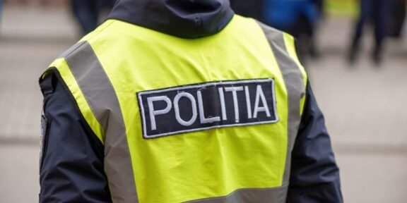 Rear view of a police officer wearing a neon yellow reflective vest with a POLITIA patch on the back.