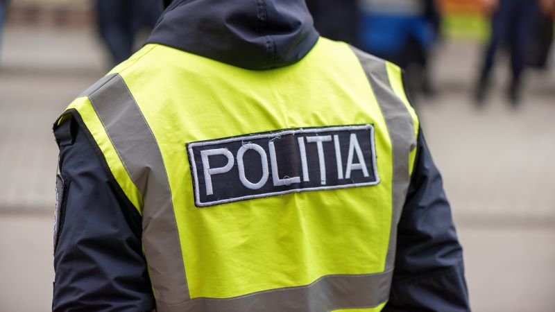 Rear view of a police officer wearing a neon yellow reflective vest with a POLITIA patch on the back.