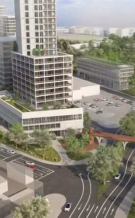 Aerial rendering of a modern urban district: a tall central tower, surrounding low-rise buildings, green parks, and an elevated pedestrian walkway weaving over curved roads.