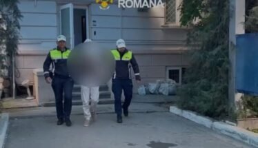 Two Romanian police officers escort a detainee with face blurred outside a building marked Politia Romana.