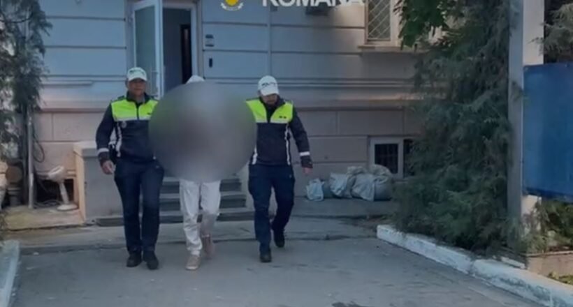 Two Romanian police officers escort a detainee with face blurred outside a building marked Politia Romana.