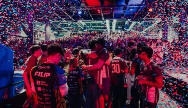 Crowded esports arena celebrating on stage with colorful confetti showering over players and fans.