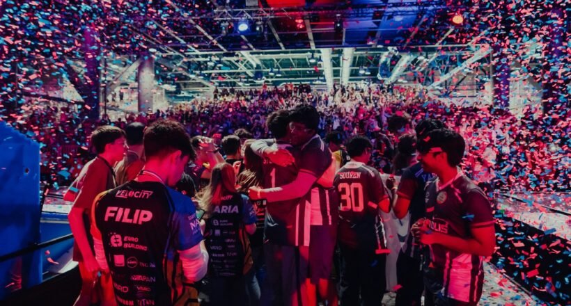 Crowded esports arena celebrating on stage with colorful confetti showering over players and fans.