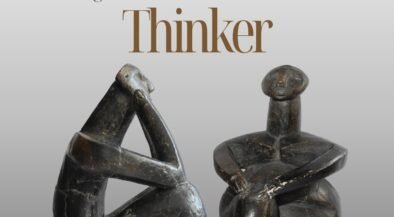 Promotional poster for The International Symposium featuring two dark abstract stone sculptures on a gray gradient background.