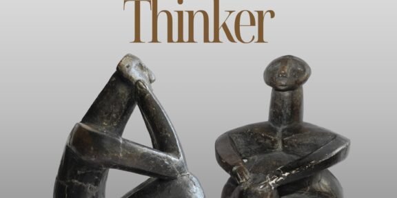 Promotional poster for The International Symposium featuring two dark abstract stone sculptures on a gray gradient background.