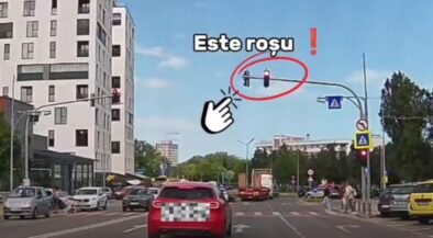 Red traffic light circled with the Romanian caption 'Este rosu' and a pointing hand for emphasis at a city intersection.