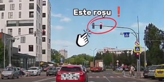 Red traffic light circled with the Romanian caption 'Este rosu' and a pointing hand for emphasis at a city intersection.