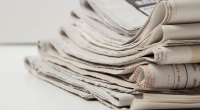 Pile of folded newspapers stacked on a white surface