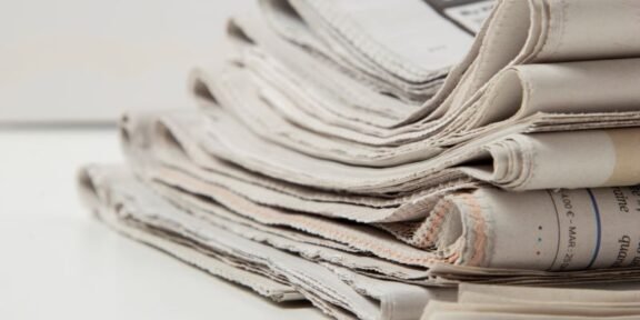 Pile of folded newspapers stacked on a white surface